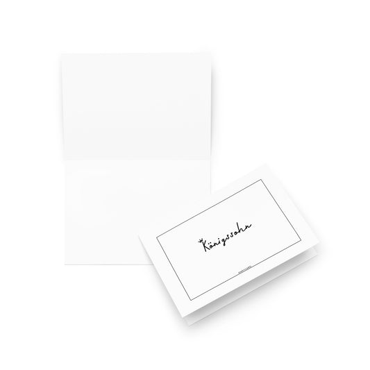 Eine geöffnete Königssohn-Karte von ohmycard steht neben ihrem Umschlag, auf dem "Königsdorf" in Schreibschrift steht. Der minimalistische weiße Hintergrund macht sie zu einem idealen Geschenk für Männer oder um eine aufmunternde Botschaft zu übermitteln.