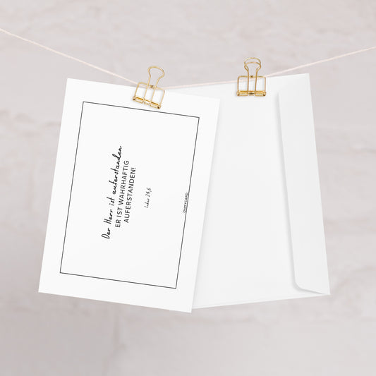 Die christliche Osterkarte "Er ist auferstanden" von ohmycard zeigt den Bibelvers "Der Herr ist wahrhaftig auferstanden! Luk 24,6" und kommt mit weißem Umschlag - stilvoll an goldenen Binderclips präsentiert.
