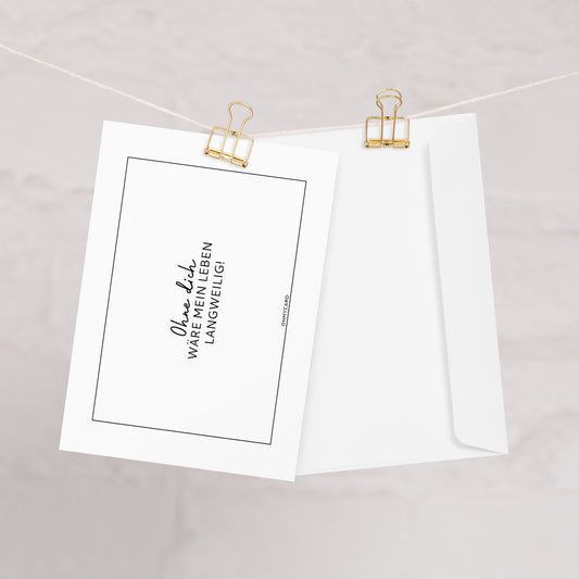 Eine weiße Grußkarte von ohmycard hängt an einer Schnur mit goldenen Klammern neben einem Umschlag. Auf der Karte steht: "Ohne dich wäre mein Leben langweilig" - eine herzliche Botschaft für Ihren Lieblingsmenschen.