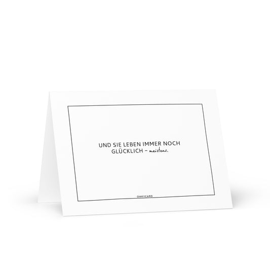Die Grußkarte "Meistens glücklich" von ohmycard ist weiß mit schwarzem Rahmen, zeigt den Spruch "UND SIE LEBEN IMMER NOCH GLÜCKLICH - meistens." und bringt Paare garantiert zum Schmunzeln.