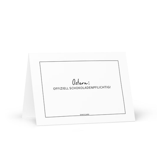 Die ohmycard "Ostern: offiziell Schokoladenpflichtig" Osterkarte zeigt schwarzen deutschen Text auf weißem Grund - perfekt für Schokoladenliebhaber. Die Karte steht offen auf einer weißen Fläche.