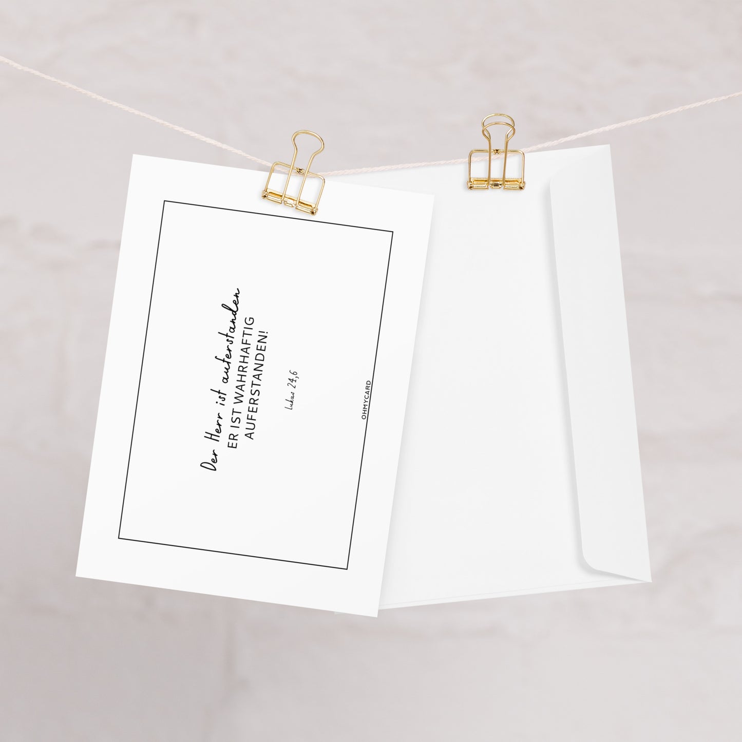 Die christliche Osterkarte "Er ist auferstanden" von ohmycard zeigt den Bibelvers "Der Herr ist wahrhaftig auferstanden! Luk 24,6" und kommt mit weißem Umschlag - stilvoll an goldenen Binderclips präsentiert.