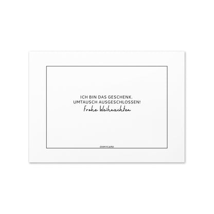 Die ohmycard "Ich bin das Geschenk" ist eine weiße Karte mit einem dünnen schwarzen Rand und deutschem Text: Ich bin das Geschenk. Umtausch ausgeschlossen! Frohe Weihnachten - perfekt für lustige Weihnachtsgrüße.