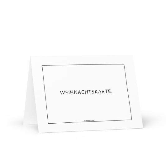 Eine schlichte weiße Weihnachtskarte von ohmycard steht aufrecht mit "WEIHNACHTSKARTE." in schwarzer Tonerfarbe gedruckt, zentriert in einem dünnen rechteckigen Rahmen. Inklusive kostenlosem Umschlag.